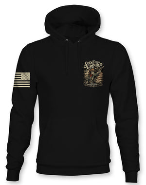 A black pullover hoodie with a distressed gold American flag graphic on the right sleeve and a gold-toned 'Stand Up Ground' graphic on the left chest, shown against a plain white background.